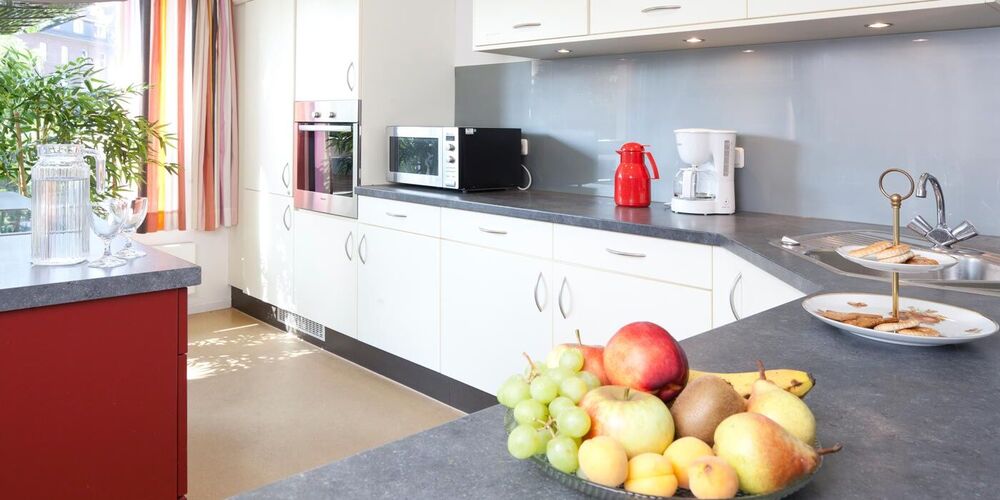 Moderne vollausgestattete Küche im Haus Raphael. Auf der Arbeitsfläche steht eine Obstschale und eine Etagere mit Keksen. 